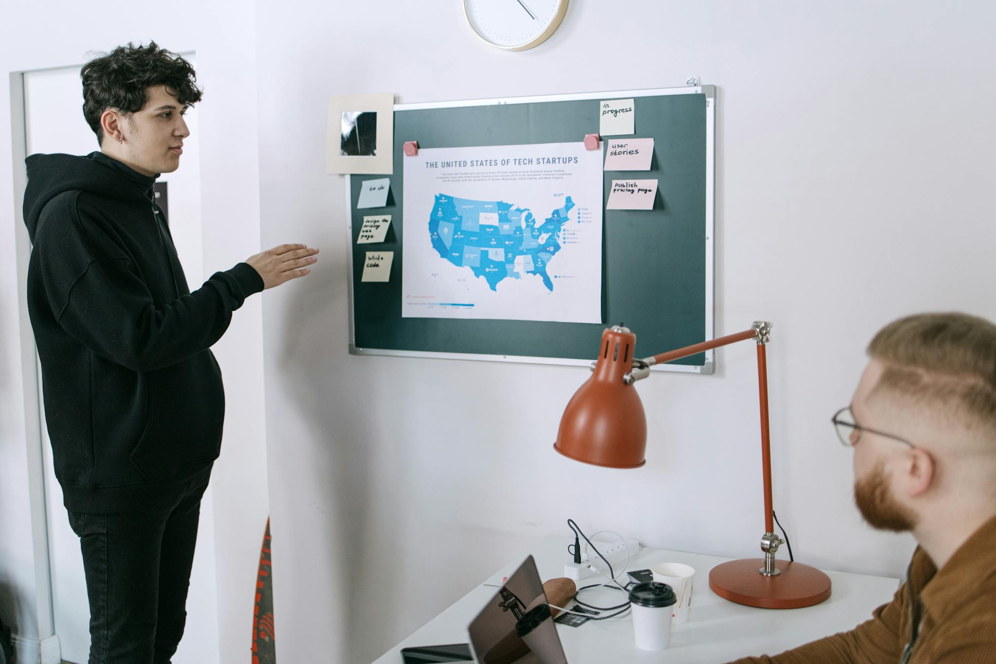 Business meeting discussing startup plans with a map of the United States in a modern office setting.